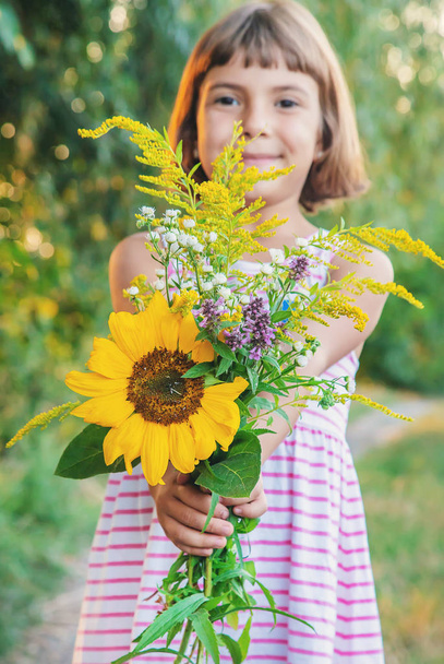 child holds a bouquet of wildflowers in his hands. Selective focus. - Photo, Image