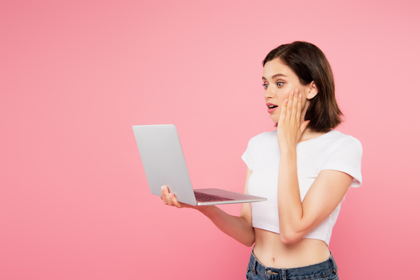 shocked pretty girl using laptop isolated on pink - Zdjęcie, obraz