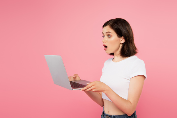 surprised pretty girl using laptop isolated on pink - Photo, Image