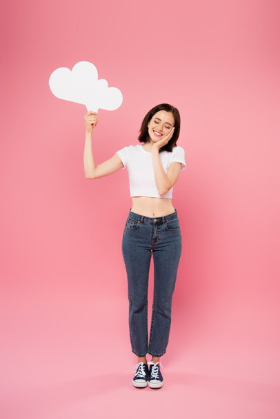 full length view of smiling pretty girl holding blank white thought bubble isolated on pink - Фото, зображення