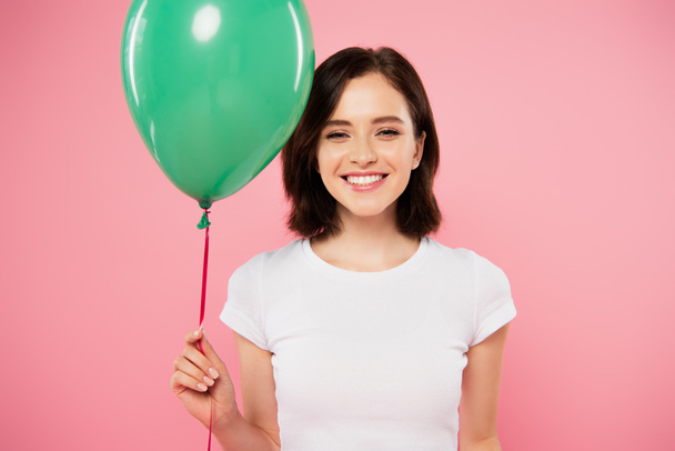 happy smiling pretty girl holding green balloon isolated on pink - 写真・画像