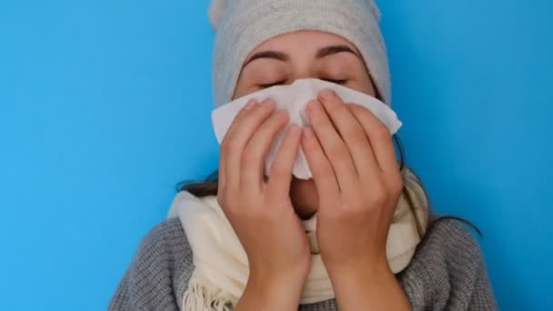 Ill allergic woman blowing running nose got flu caught cold sneezing in tissue isolated on blue blank studio background, sick female student girl having hay fever allergy symptoms holding handkerchief - Imágenes, Vídeo
