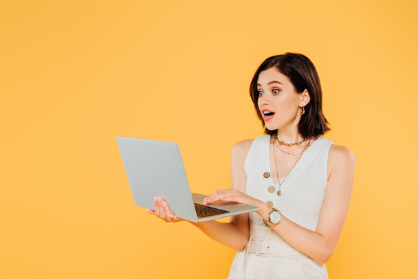 shocked elegant girl with laptop isolated on yellow - Photo, Image