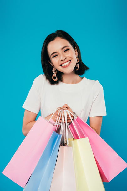smiling elegant woman in dress with shopping bags isolated on blue - Фото, зображення