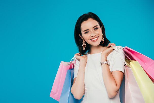 青で孤立したショッピングバッグを持つドレスで笑顔エレガントな女性 - 写真・画像