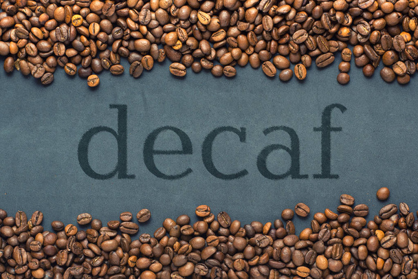 Primo piano di chicchi di caffè su sfondo grigio con l'iscrizione decaffeinato
 - Foto, immagini