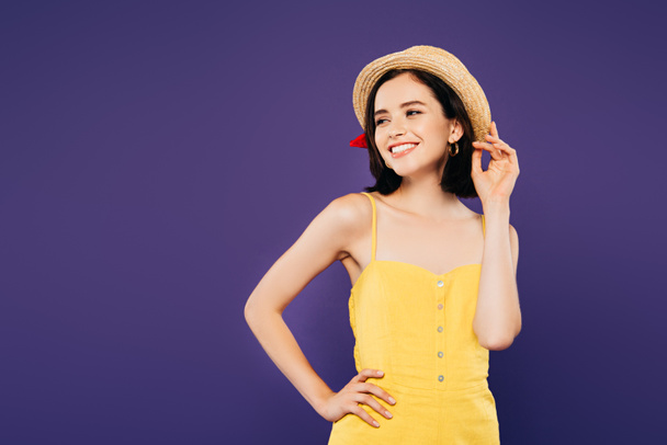 fille souriante en chapeau de paille avec la main sur la hanche regardant loin isolé sur violet
 - Photo, image