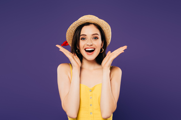smiling girl in straw hat showing surprise gesture isolated on purple - Foto, afbeelding