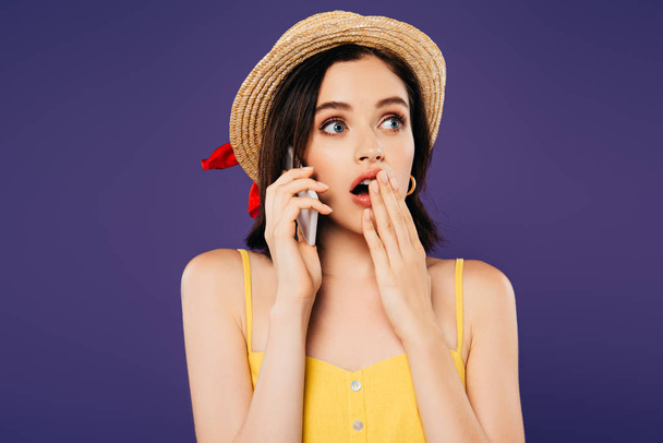 shocked girl in straw hat talking on smartphone isolated on purple - 写真・画像