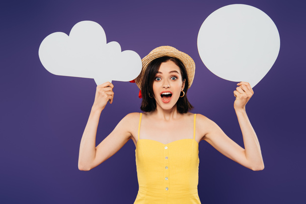 excited girl in straw hat holding empty white thought and speech bubbles isolated on purple - Photo, image