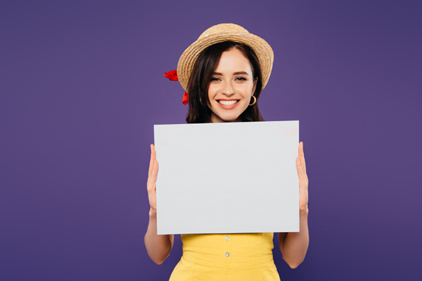 happy girl in straw hat holding empty board isolated on purple - 写真・画像
