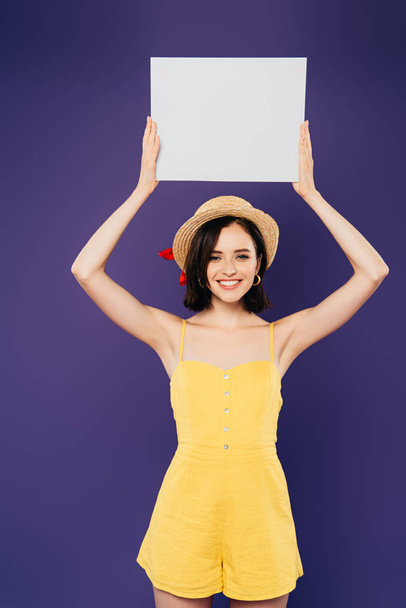 happy girl in straw hat holding empty board above head isolated on purple - Photo, Image