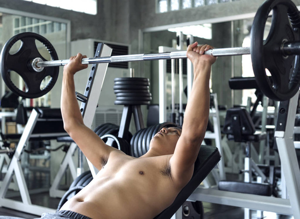 Jovem asiático homem levantando sinos no ginásio. estilo de vida saudável e conceito de motivação de treino
. - Foto, Imagem