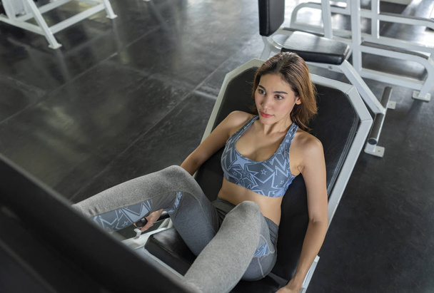 Молода азіатська жінка важить підйомник робить ноги преси в тренажерному залі. здоровий спосіб життя і мотивація тренування концепція
. - Фото, зображення