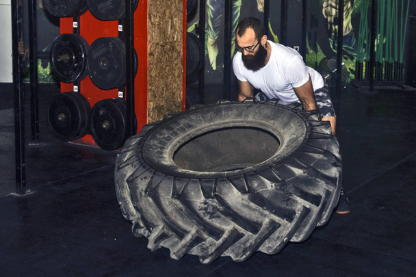 Young sportsman turning a large tire - Valokuva, kuva