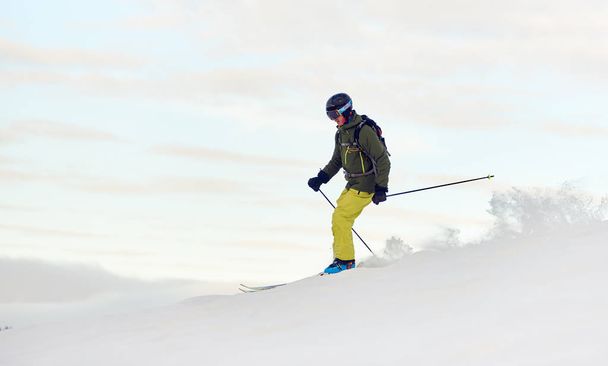 高い斜面からダウンレースバックパック付きの熟練したスキーヤー - 写真・画像