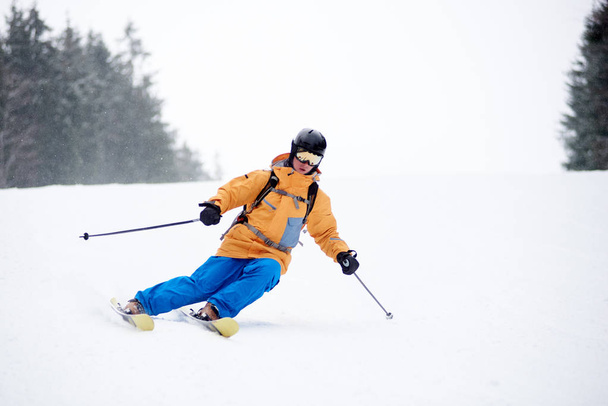 Widok z przodu młodego człowieka narciarza skręcającego z drugiej strony na kolejny łuk narciarstwa po pokrytej śniegiem drodze - Zdjęcie, obraz