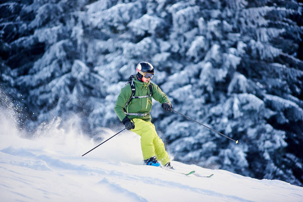 Esquiador con mochila haciendo freeride-descenso en pendiente cubierta de nieve en nieve blanca nieve polvo ventisca
 - Foto, Imagen