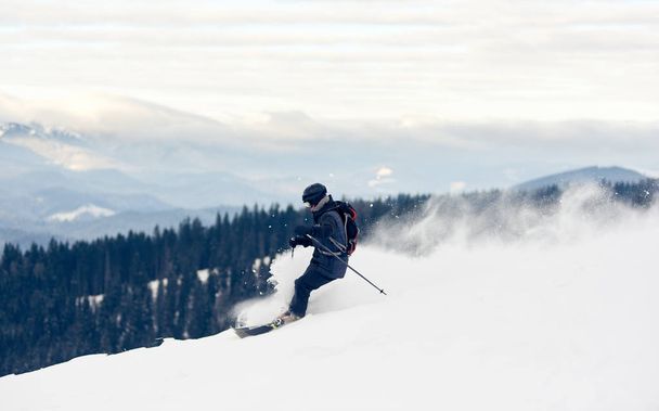 Zijaanzicht van freerider skiër afdaling van de berg in diep wit sneeuw poeder - Foto, afbeelding