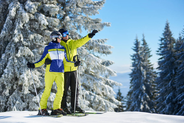 Ευτυχισμένο ζευγάρι αγκαλιάζει και απολαμβάνει θέα στο βουνό και το τοπίο στο χειμερινό φως του ήλιου - Φωτογραφία, εικόνα