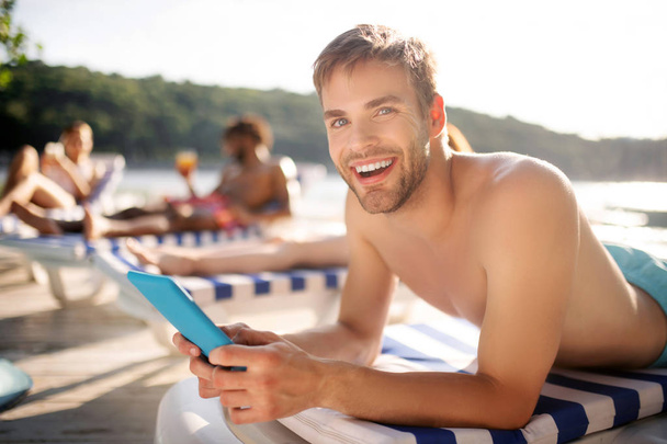Man holding tablet while having rest near river with friends - Foto, imagen