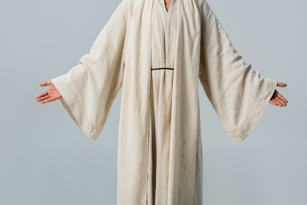 bijgesneden beeld van de mens in Jezus gewaad met uitgestrekte handen geïsoleerd op grijs  - Foto, afbeelding