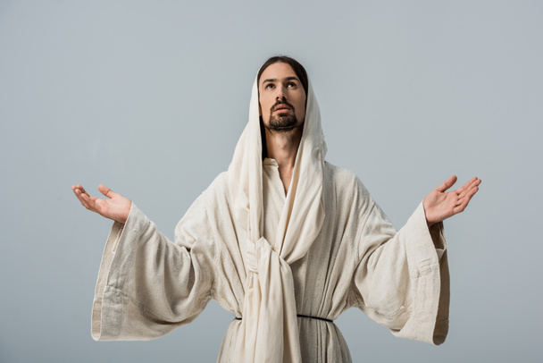religieuze man in Jezus gewaad met capuchon en uitgerekt handen geïsoleerd op grijs - Foto, afbeelding