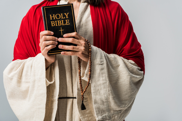 bijgesneden beeld van de man houden Heilige Bijbel en rozenkrans brood geïsoleerd op grijs  - Foto, afbeelding