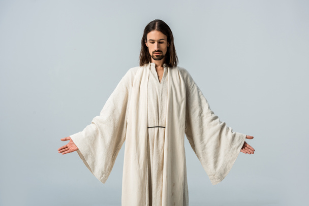 イエスのローブを着た男は、灰色で隔離された伸びた手で立っている - 写真・画像
