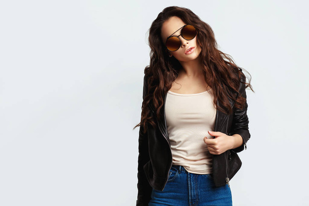 Молода красива жінка в чорній куртці і сонцезахисних окулярах
 - Фото, зображення