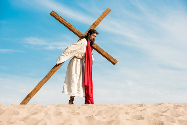 jesus in wreath walking with cross in desert  - Photo, Image