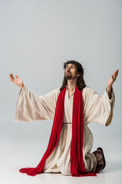 bearded man in wreath praying on knees with outstretched hands on grey  - Foto, Imagem