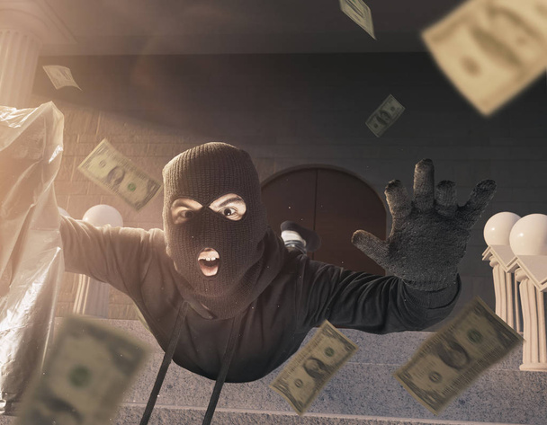 thief with balaclava and moneybag slipping and falling on the st - Фото, изображение