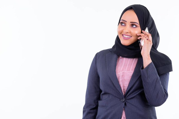 Feliz joven mujer de negocios musulmana africana pensando mientras habla por teléfono
 - Foto, imagen