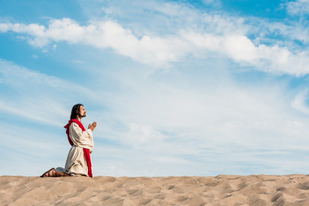людина молиться на колінах у пустелі на небі
  - Фото, зображення