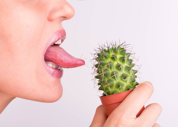 Girl licks tongue prickly cactus. - Zdjęcie, obraz
