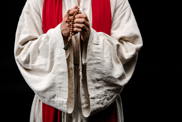 cropped view of religious man holding rosary beads isolated on black  - Foto, Imagem