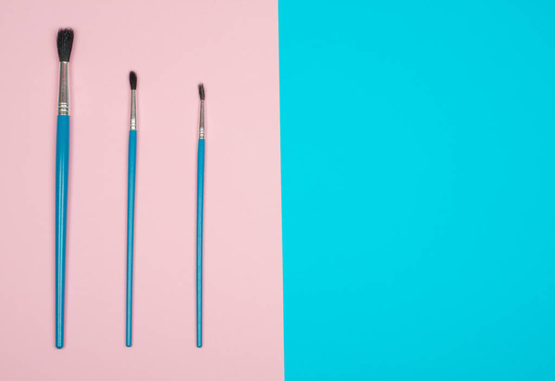 Three paintbrushes on the pink and blue background - Photo, Image