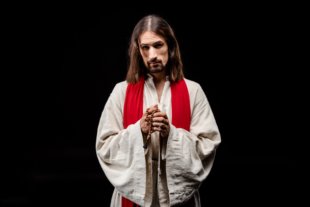 θρησκευόμενος άνθρωπος που κατέχει Ροζάριο χάντρες απομονωθεί σε μαύρο  - Φωτογραφία, εικόνα