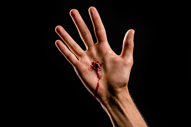 wykadrowany widok religijnego człowieka z krwawą ręką wyizolowaną na czarno  - Zdjęcie, obraz