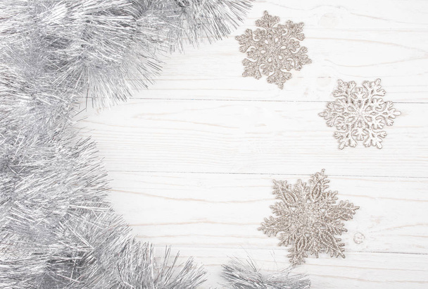 Silver tinsel and snowflakes on a wooden background - Photo, Image