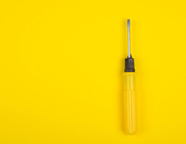 Single yellow screwdriver on a bright yellow background - 写真・画像