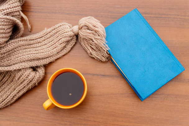Чашка кофе, вязаный шарф и книга на деревянном фоне
 - Фото, изображение