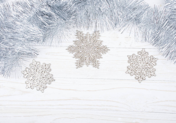 Silver tinsel and snowflakes on a wooden background - Fotoğraf, Görsel