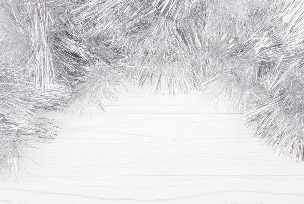 Silver tinsel on a white wooden background - Фото, изображение