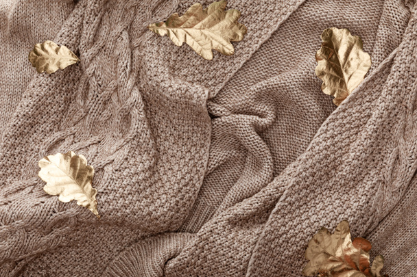 pohled na zlatý listoví roztroušené po pleteném hnědoušním svetru - Fotografie, Obrázek
