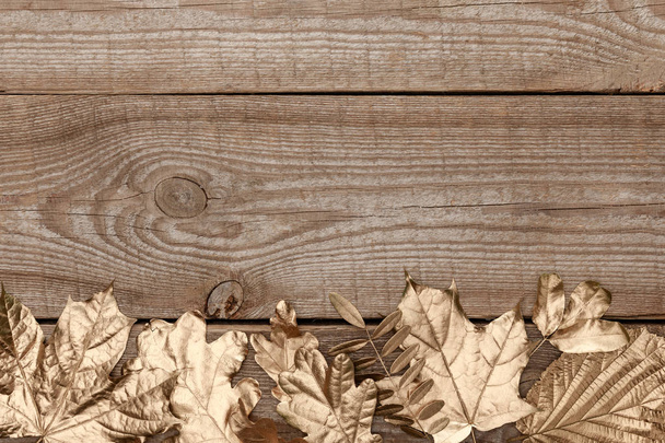 top view of golden leaves on wooden textured background - Fotoğraf, Görsel