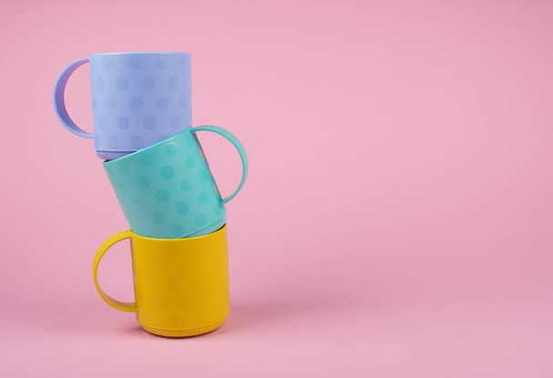 Stack of colorful cups on a pastel pink background - Foto, immagini