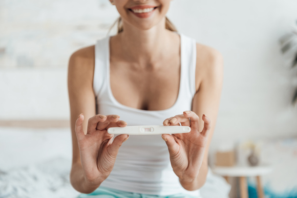 partial view of smiling young woman showing pregnancy test  - Foto, afbeelding