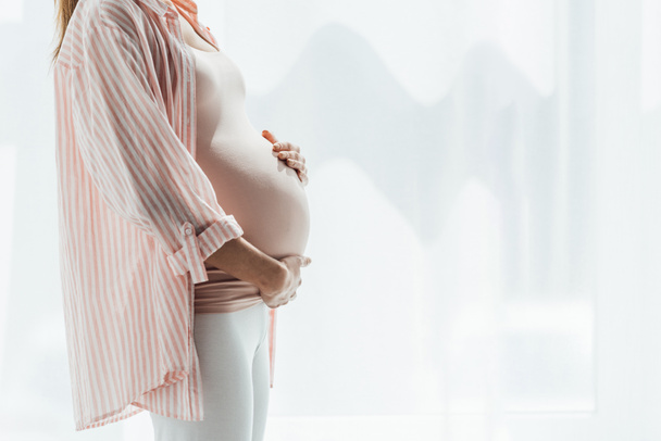 cropped view of pregnant woman touching belly at home - Foto, Imagen